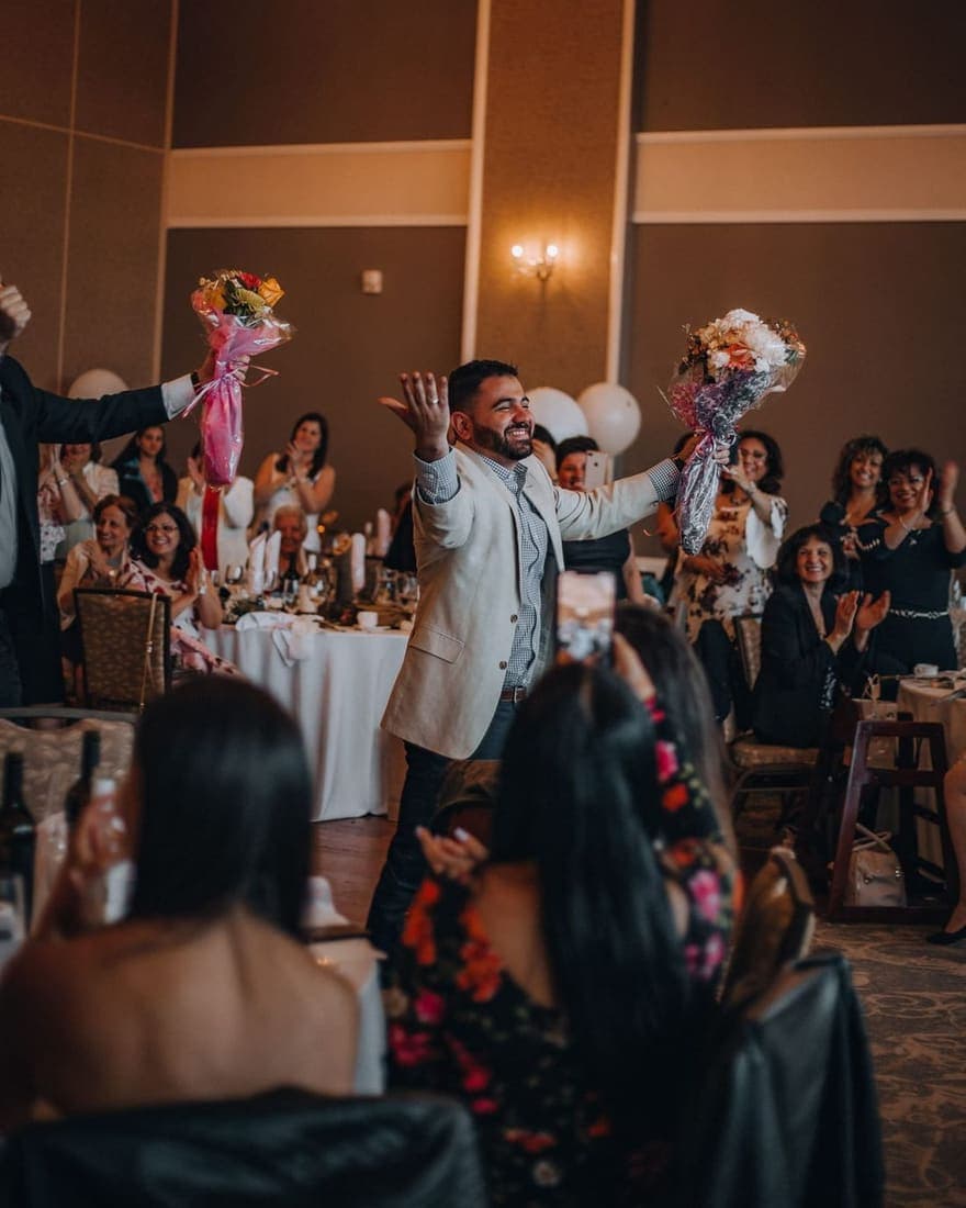 Un invitato festeggia al ricevimento mentre gli altri lo riprendono col telefono